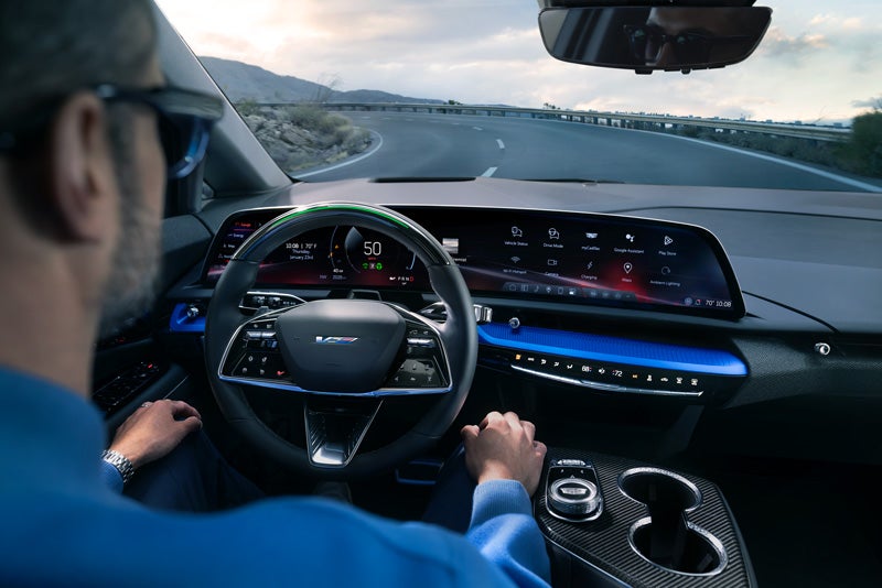 Front View of the 2026 OPTIQ-V Driving Through the Dusk Utilizing its Headlights | Stephen Cadillac in Bristol CT
