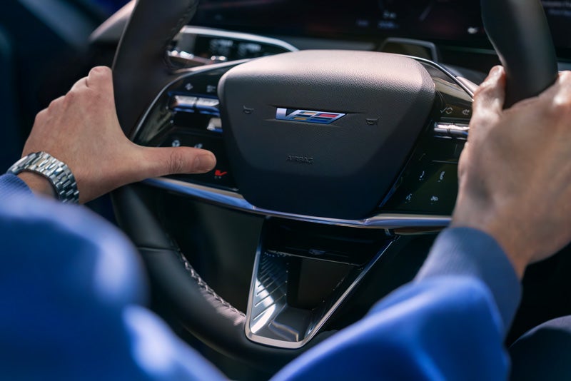 Close-up of a Man About to Press the V-Button on the 2026 OPTIQ-V Steering Wheel | Stephen Cadillac in Bristol CT